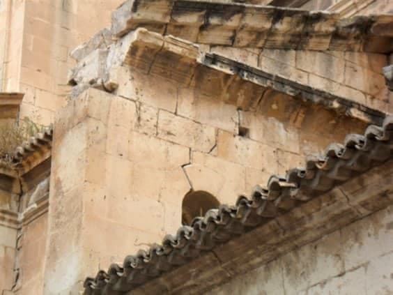Figura 3. Fotografía de daños observados a simple vista desde el exterior. Caída del pináculo ubicado en extremo del contrafuerte y parte de la cornisa. Grieta sobre arco situado en el paño del propio contrafuerte y descenso de la clave del arco. Se puede observar también vegetación en zona de cubierta que refleja una falta de mantenimiento.